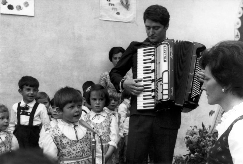 04-Franco barbier alla fisarmonica, la maestra dell'asilo e i bambini che cantano. San Gregorio nelle Alpi, pimi anni sessanta..jpg