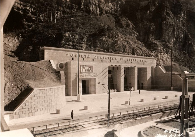 59) Centrale idroelettrica, grande manufatto in cemento armato, rivestito in pietra rosata, di chiara architettura razionalista fascista. E' la porta d'accesso alla centrale idroelettrica in caverna di La Stanga...jpg