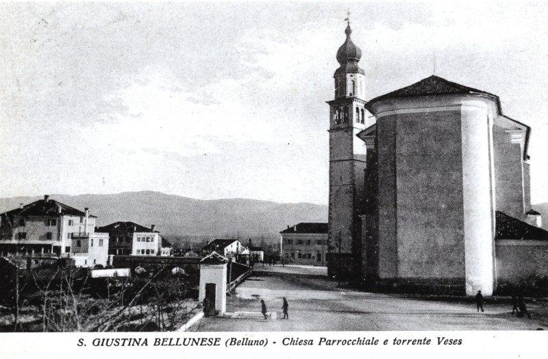 68) Santa Giustina bellunese con la chiesa parrocchiale, torrente Veses e la pesa pubblica nella piazza dietro alla chiesa.jpg
